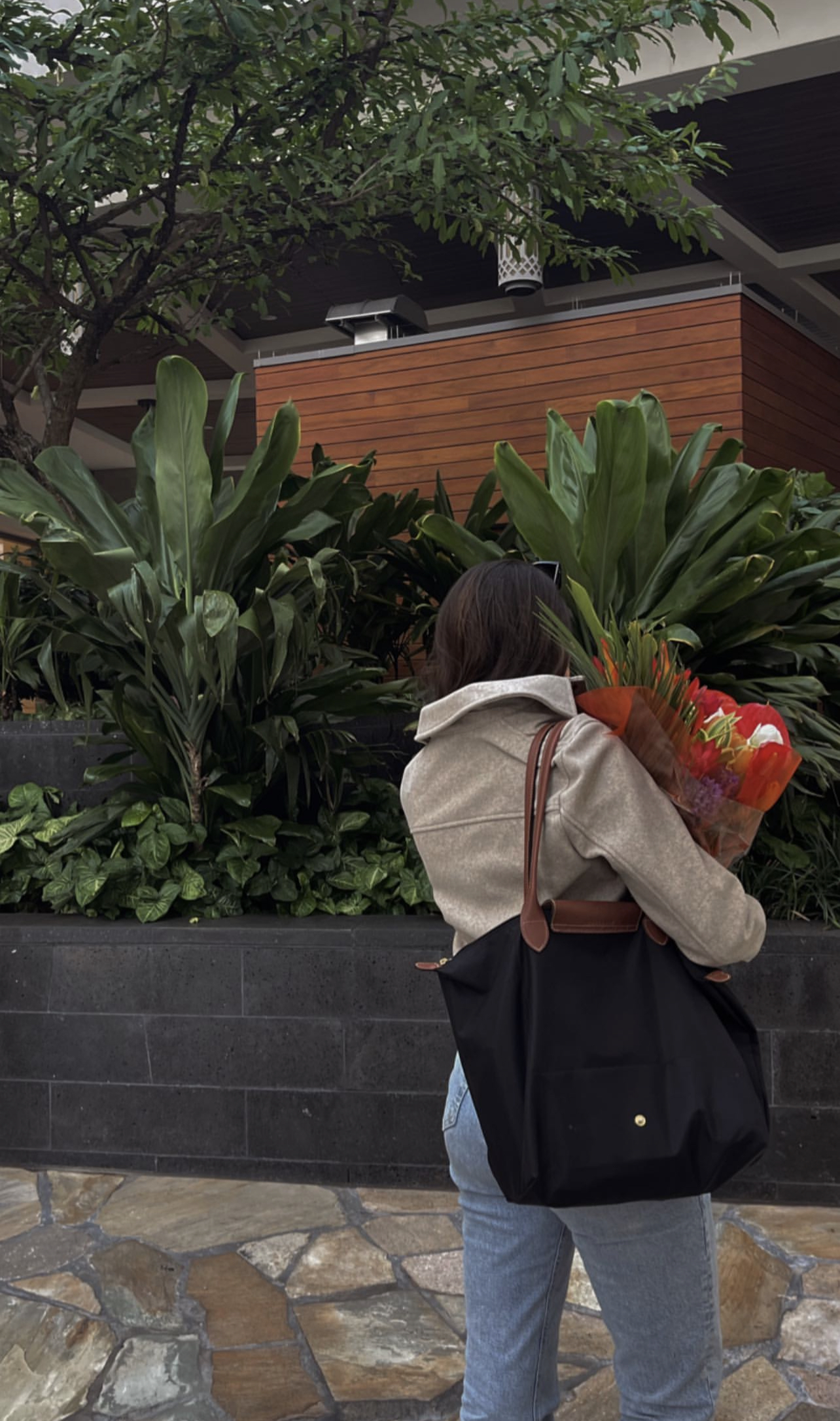 Girl carrying flowers with Longchamp tote, view from behind